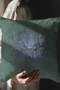 A pillow cover featuring a serene stag's face detailed in soft lavender, surrounded by radiating light beams on forest green fabric. Tiny stars twinkle throughout the design.